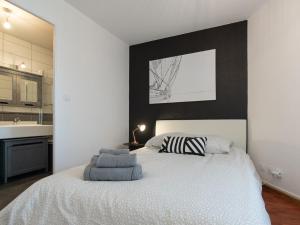 ein Schlafzimmer mit einem weißen Bett und einer schwarzen Wand in der Unterkunft Le Piccandet in Saint-Genis-les-Ollières