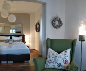 a bedroom with a bed and a green chair at Ferienwohnung WohlfühlEckerl in Tittmoning