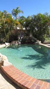 a swimming pool in a resort with a rock wall at Heritage Lodge Motel in Charters Towers