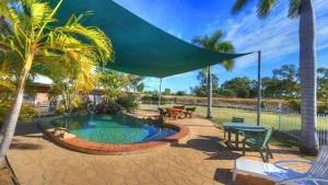 a patio with a swimming pool with a large umbrella at Heritage Lodge Motel in Charters Towers