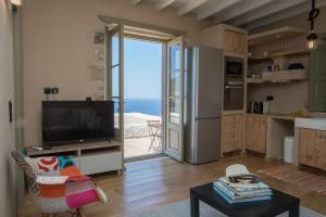 a living room with a television and a kitchen with a view at Sunset & Ocean view Villa in Patmos