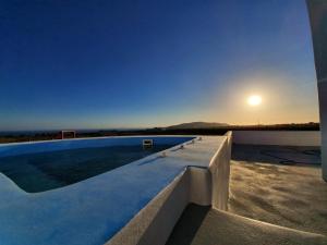a swimming pool on the roof of a house with the sunset at Villa Therme Athena in Emporio Santorini
