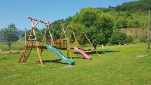 um parque infantil com escorregas e um baloiço num campo em Villa Richka em Richka