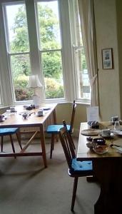 een woonkamer met een tafel, stoelen en ramen bij Aydon House in Alnwick