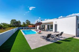 a backyard with a swimming pool and grass at Holiday Home Gabriella in Poljica