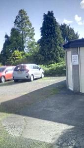 dois carros estacionados num parque de estacionamento ao lado de um edifício em Aydon House em Alnwick