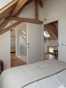una camera con letto bianco in una stanza con soffitti in legno di Kompas gîte a Ellezelles