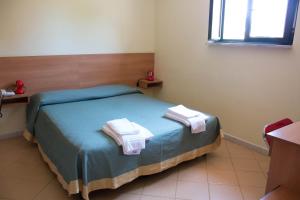 una camera da letto con un letto con asciugamani sopra di Hotel Kennedy a Metaponto