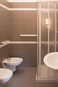 ein Badezimmer mit zwei Waschbecken, einer Dusche und einem WC in der Unterkunft Hotel Kennedy in Metaponto