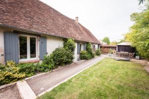 a house with a wooden walkway next to a yard at le clos du puits in Maslives