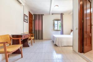 1 dormitorio con cama, escritorio y mesa en Hotel Canadá en Tarragona