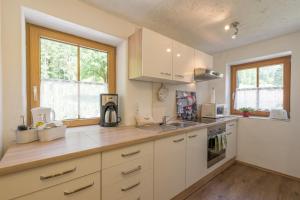 a kitchen with white cabinets and a sink at Berggasthof Riefenkopf in Oberstdorf