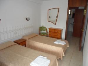 a hotel room with two beds and a mirror at Apartamentos Cervantes in Benidorm