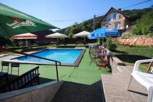 a pool with tables and chairs and an umbrella at Penzion Paseky U Zapadlych vlastencu in Paseky nad Jizerou