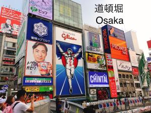 a crowd of people standing in a city with signs at Ryokoheya Tenrokukan in Osaka