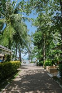 a street with palm trees and the ocean in the background at Aonang Buri Resort- SHA Extra Plus in Ao Nang Beach