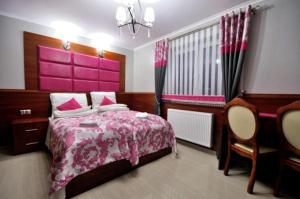 ザコパネにあるApi IV Zakopaneのピンクベッド1台とデスク付きのベッドルーム1室