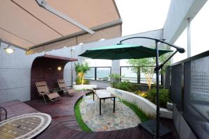 Dunsan Graytone Hotel في دايجون: فناء مع طاولة ومظلة خضراء