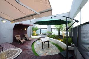 a patio with a table and a green umbrella at Dunsan Graytone Hotel in Daejeon