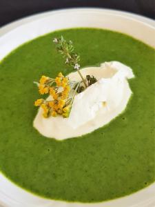 a bowl of green soup with flowers in it at Maison d'Hôtes Zella in Bains de Guitera