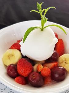 a bowl of fruit with strawberries bananas and cherries at Maison d'Hôtes Zella in Bains de Guitera