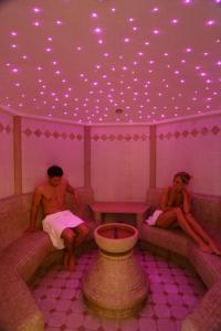 two people sitting on benches in a room with purple lights at Residence Mühlegg in Valdaora