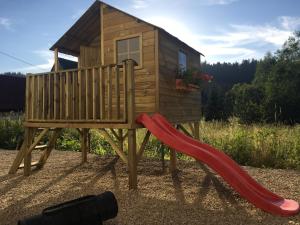 a playground with a house and a slide at Apartamenty Na Przełaj - LUX - zewnętrzna sauna fińska i zewnętrzne gorące jacuzzi - cały rok! in Poronin