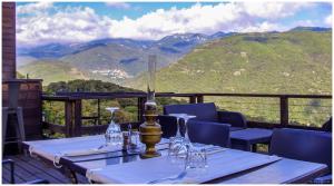 a table with wine glasses on a balcony with mountains at Maison d'Hôtes Zella in Bains de Guitera