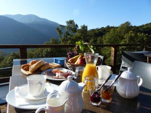 a table with a plate of food and a basket of bread at Maison d'Hôtes Zella in Bains de Guitera