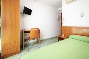 a bedroom with two beds and a desk and a chair at Hotel Mavi in Gandía