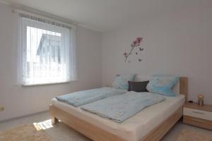 a bedroom with a bed with blue sheets and a window at Ferienhaus "Am Eisenberg"- Wandern im UNESCO Biosphärenreservat Vessertal in Schmiedefeld am Rennsteig