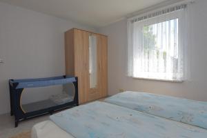 a bedroom with two beds and a cabinet and a window at Ferienhaus "Am Eisenberg"- Wandern im UNESCO Biosphärenreservat Vessertal in Schmiedefeld am Rennsteig +9 photos