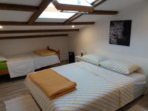 a bedroom with two beds and a skylight at Apartman Lea in Brodarica