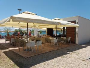 a restaurant with tables and chairs under umbrellas at Apartman Lea in Brodarica