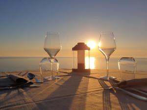 Resort Faro di Punta Fenaio في كامبيس: طاولة مع كؤوس للنبيذ ومنارة على الشاطئ