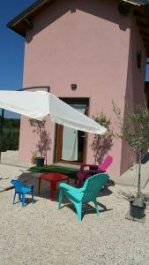 un grupo de sillas y una sombrilla frente a una casa en Casale dei Lamponi a "le Moline" vita in fattoria, en Vetralla