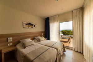 a bedroom with two beds and a large window at Hotel Tamariu in Tamariu