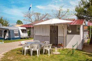 a table with chairs and an umbrella in front of a house at Camp Mali bungalow in Baška