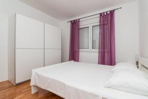 a bedroom with a white bed and a window at Apartment Bambi in Mali Lošinj