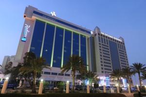a large building with palm trees in front of it at The Diplomat Radisson Blu Residence in Manama