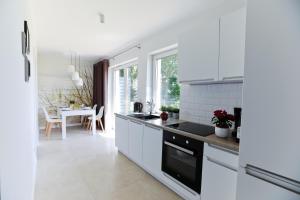 a kitchen with white appliances and a dining room at M&K Apartamenty - Morska Bryza, Sobieszewo- Wyspa Sobieszewwska in Gdańsk
