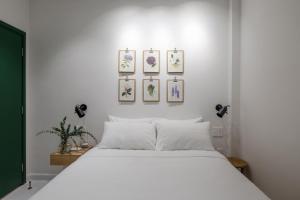 um quarto com uma cama branca com quatro fotografias na parede em Botanist Lab Minihotel by CIRCADIAN em Ho Chi Minh