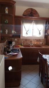 een keuken met houten kasten, een wastafel en een raam bij Pitsinis Apartments II in Roda
