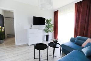 a living room with a blue couch and a tv at M&K Apartamenty - Morska Bryza, Sobieszewo- Wyspa Sobieszewwska in Gdańsk