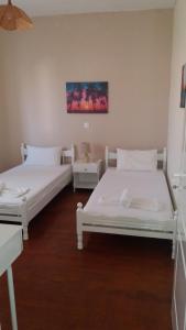 twee bedden in een kamer met witte muren en houten vloeren bij Pitsinis Apartments II in Roda