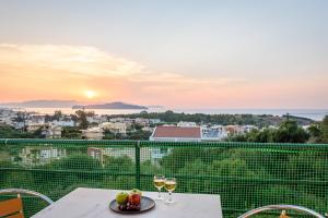 a table with two glasses of wine on a balcony with the sunset at Golden Beach Hill Apartments in Kato Daratso