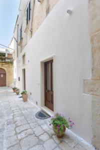 a white building with a door and some potted plants at I Battenti in Galatina