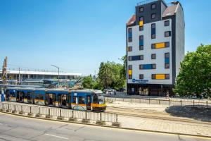un treno blu e giallo su binari accanto a un edificio di Best Western Terminus Hotel a Sofia