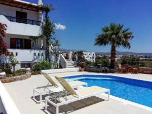a villa with a swimming pool and two lounge chairs at Dina Naxos Studios in Agios Prokopios