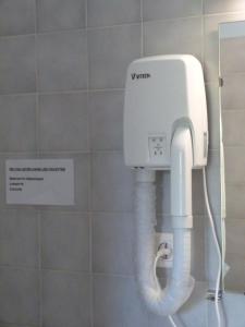 secador de pelo blanco en un baño con pared en Le Chalet, en Antrenas